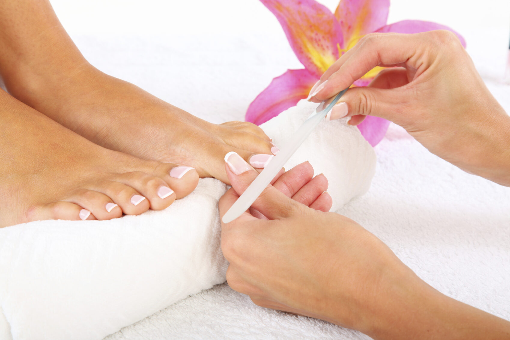 Pedicure: teennagels worden gevijld op een witte handdoek