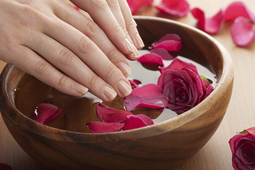 Spa manicure: handen in een schaal met water en rozenblaadjes